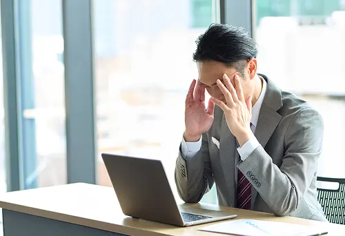仕事で頭を抱える男性